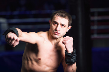 Fototapeta na wymiar Sports: man kickboxer is practicing kick in a boxing gym