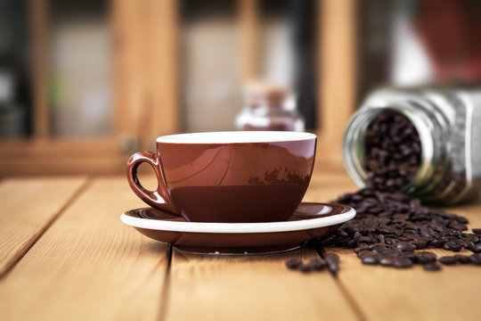 Cup coffee on a wooden table with scattered coffee beans