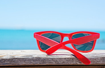 Red sunglasses on blue sea  and sky background