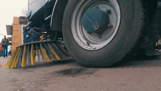 Car of cleaning streets goes forward and sweeping the sidewalk