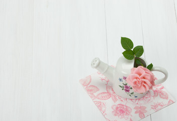 Rose Flower In Porcelain Watering Can. White Table.