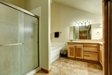 Elegant bathroom in soft tones with hardwood cabinets and marble tiled floor.