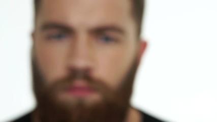 Handsome young serious man with red beard looking at camera and steps back