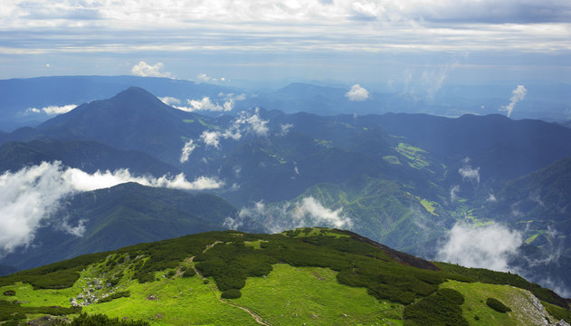 View from the top of Kordezeva Glava / Peca hill, Karavanke mountain range, Slovenia / Austria - beautiful scenery of peaks during dramatic overcast with clouds