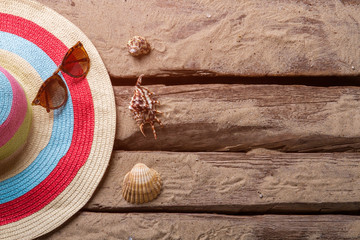 Beach hat and seashells. Seashells next to sunglasses. Greetings from a tropical island. Take these souvenirs home.