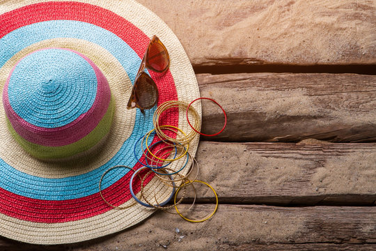 Beach hat and bracelets. Hat with bracelets and sunglasses. Girl's beach accessories. Floor of beach house.