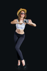 a smiling charming girl with long brown hair in a hat holding a camera in the black background for...