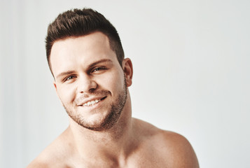 Obraz premium Handsome young man in casual white top against bright beach background
