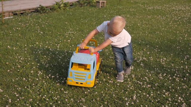 Adorable Little Blond Boy Playing With Big Car Outdoors.