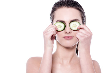 Attractive woman covering her eyes with cucumber.