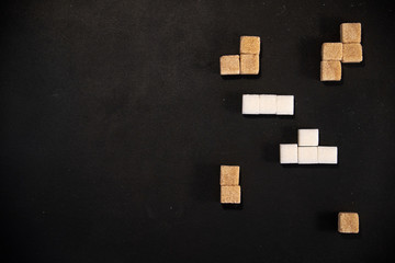 Cubes of white and brown sugar arranged in tetris shapes with black background and copyspace
