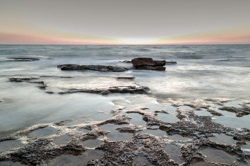 Fototapeta na wymiar Silky water on the rocks after sunset, Nahariya, HDR painterly