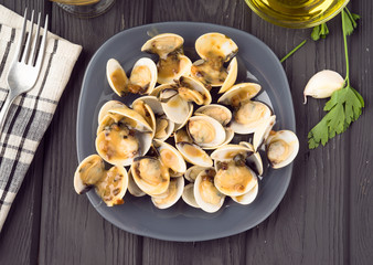 overhead shoot full of clams in sauce dish over wood gray