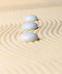 Fototapeta na wymiar Composition three white stones on yellow sand - Zen Garden