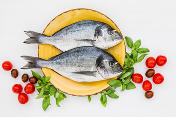Fresh dorado fish on plate with vegetables. Top view