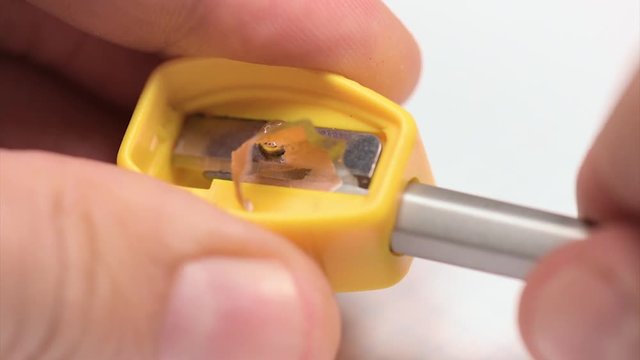 Close up of male hands sharpening a pencil on white background