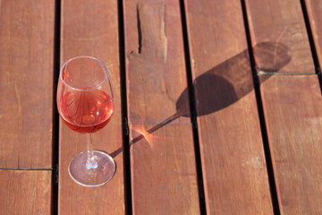 A glass of rosé wine on wooden table