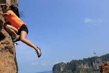 young woman rock climber climbing at seaside mountain rock