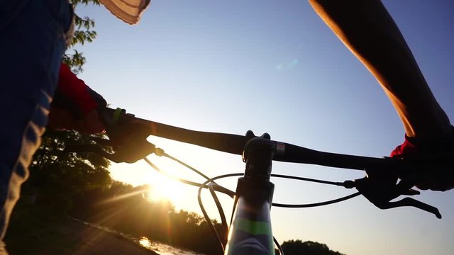Girl cyclist in gloves walking with her bike. Slow motion shot against sunset
