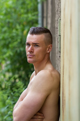 Naklejka na ściany i meble attractive man / Young, attractive, sporty man leaning against a wall