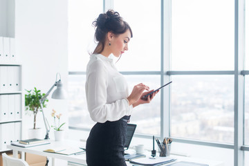 Close-up side view portrait of an employee texting, sending and reading messages during her break at the workplace.