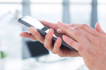 Close-up side view picture of female hands holding smartphone, using apps and wi-fi internet,...
