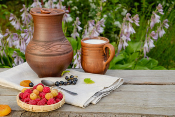 Raspberries in the basket. Clay dishes. In the garden.