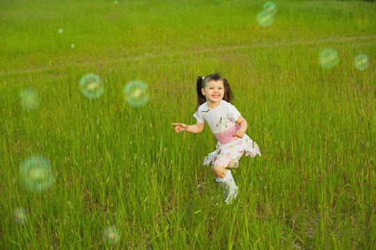 Happy little girl among soap bubbles
