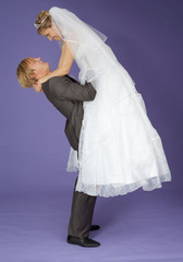 Strong groom holds admired bride on hands