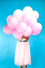 Unrecognizable girl with many pink balloons