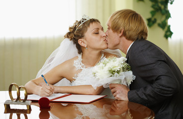 Bride and groom kiss during ceremony of marriage