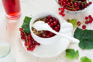 Healthy breakfast: muesli with yogurt and fresh berries in a bowl and juice on white wooden background