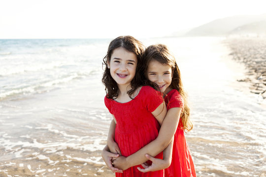 Two happy little sisters standing at seafront