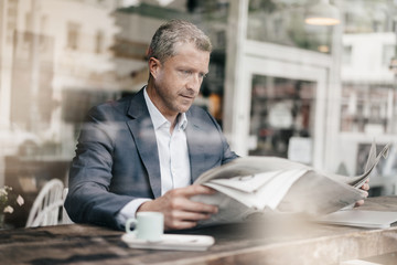 Businessman in cafe reading newspaper