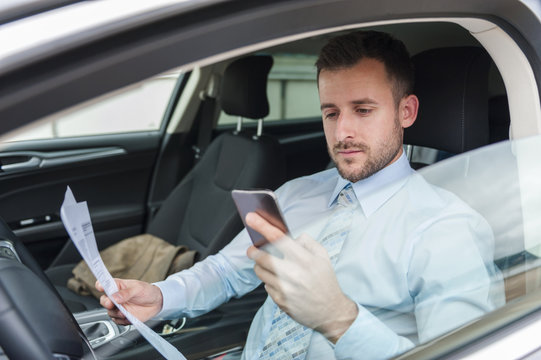 Businessman With Documents And Cell Phone In Car