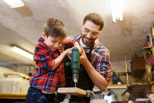 Father And Son With Drill Working At Workshop