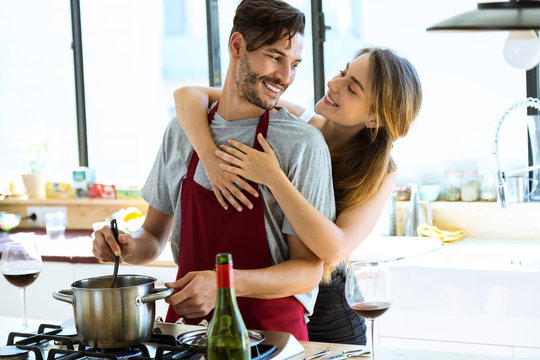 Happy young couple cooking together in the kitchen at home.