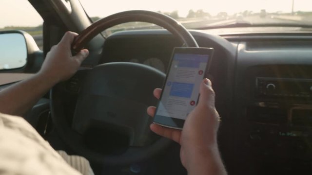 Over the shoulder close-up shot of putting down the phone while driving on a busy freeway.
