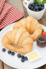 Fresh tasty croissants with butter, jam and berry.