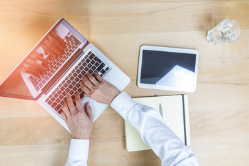 Elevated view of desk with hands, laptop, tablet and notebook