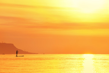 sunrise over the sea and silhouette of a man rowing  SUP  Stand Up Paddling
