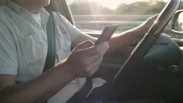 Over the shoulder shot of a man using his cellphone while driving.
