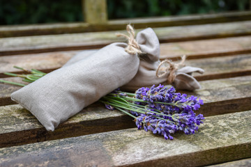 Fresh lavender flowers and canvas fragrant bag with dried lavender flowers on rustic wooden bench.