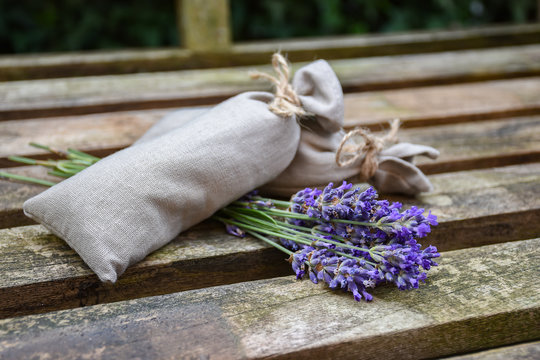 Fototapeta Fresh lavender flowers and canvas fragrant bag with dried lavender flowers on rustic wooden bench.