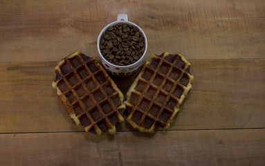 Obraz na płótnie Canvas Two sweet waffles with cup full of coffee beans