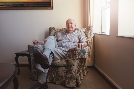 Relaxed elderly man sitting on a arm chair - Powered by Adobe