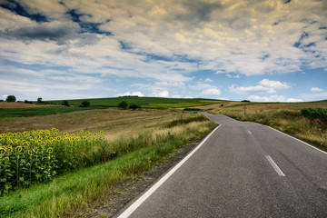 Fototapeta na wymiar Countryside landscape and road on a cloudy sky