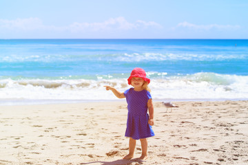 cute little girl pointing at sand beach