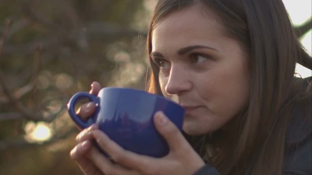 Woman blowing on the tea to cool down.