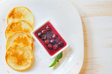 Pancakes with cherry jam in square  plate on the wooden table